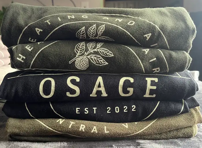 A stack of folded Osage shirts printed OSAGE Heating and Air, Est 2022