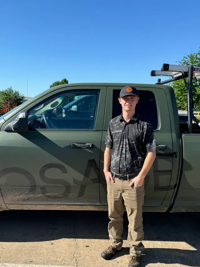 An Osage technician standing beside the olive OSAGE truck