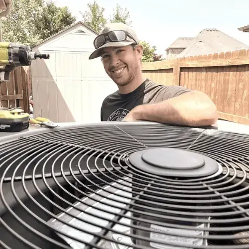 An Osage technician leaning over a condenser fan after a repair